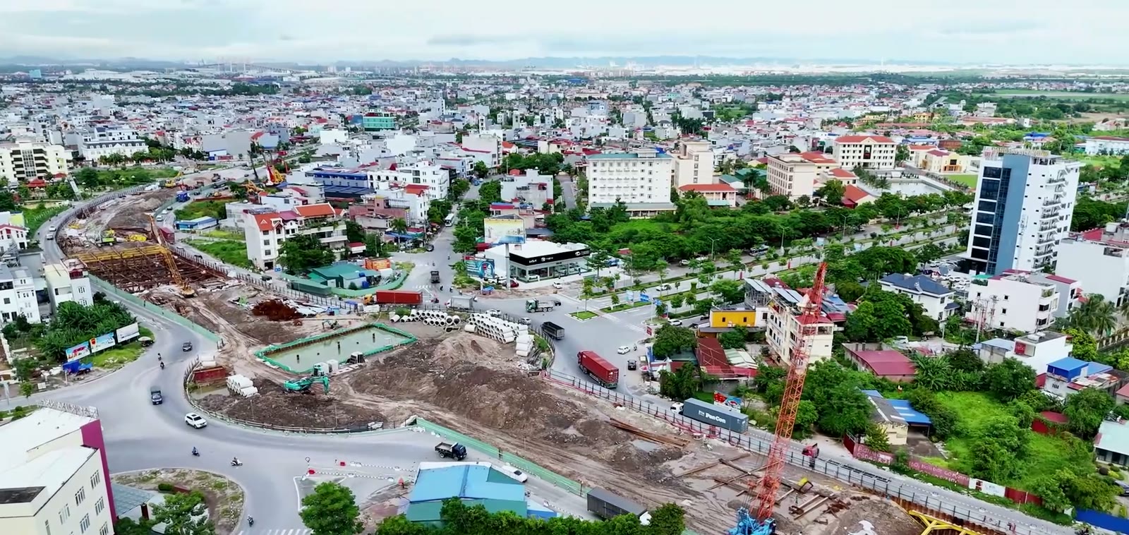 Công trường hầm chui Bùi Viện Lê Hồng Phong với giàn thanh chống thép màu vàng, cần cẩu, đốt cống bê tông xếp bãi và xe container chạy vòng quanh hàng rào