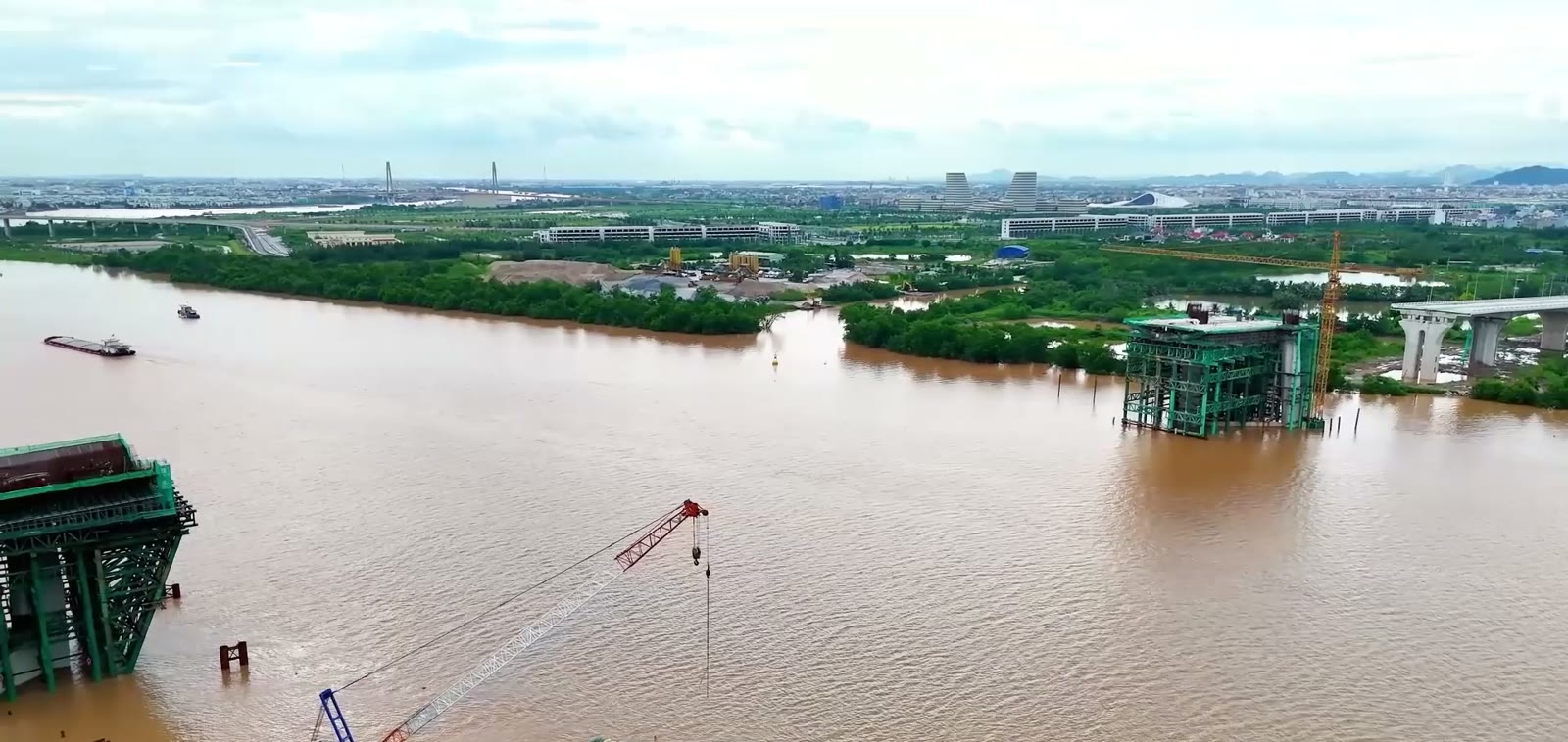 Hai trụ tháp cầu Nguyễn Trãi nhô lên từ sông Cấm, phía bờ bên kia là các tòa nhà của trung tâm hành chính mới Thủy Nguyên Hải Phòng