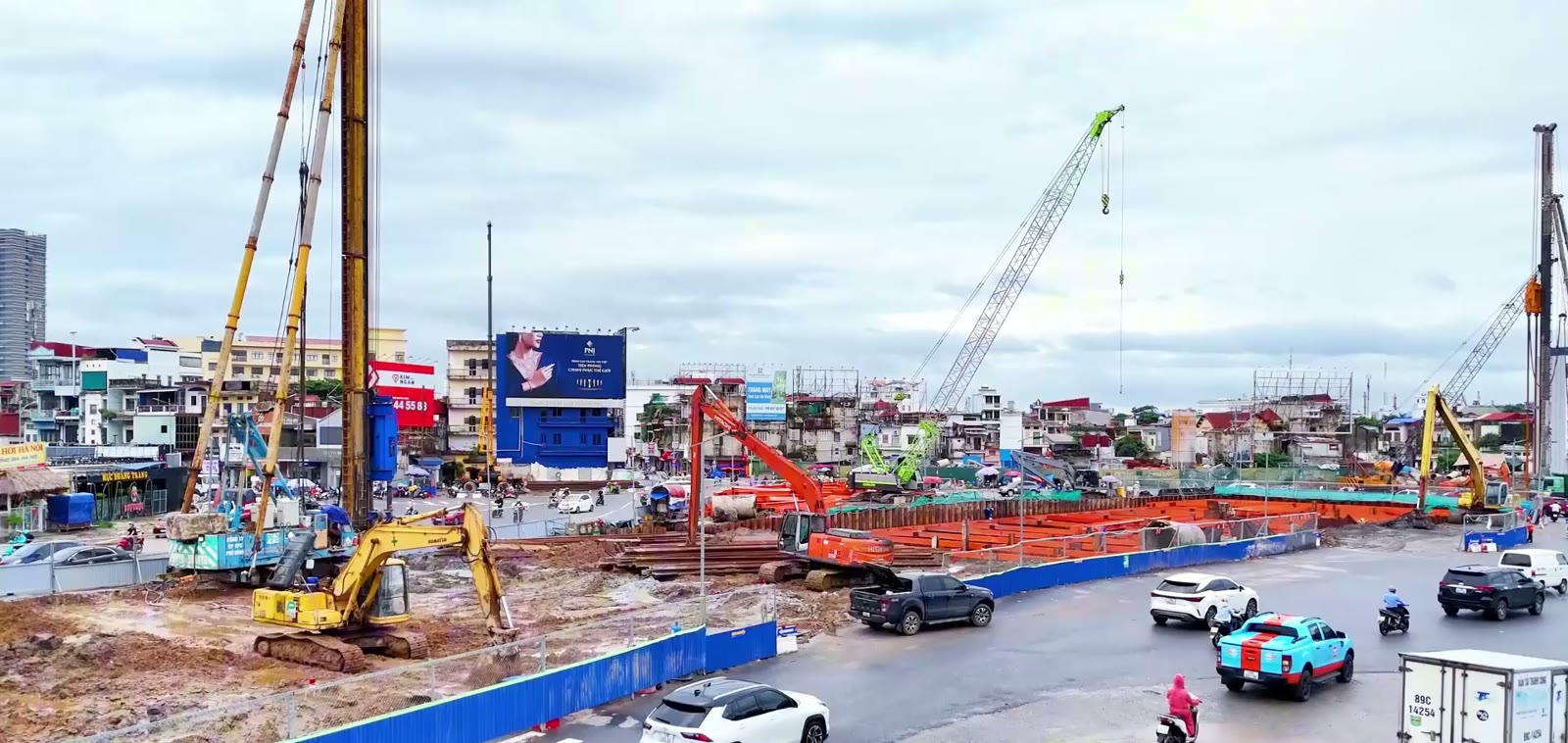 Hố đào hầm chui tại ngã 6 Lạc Viên Hải Phòng với giàn thanh chống màu cam, hai máy khoan cọc và dòng xe chạy vòng quanh hàng rào công trường