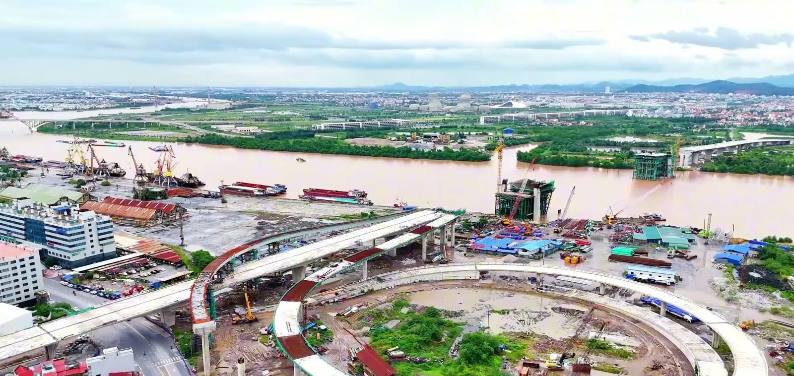 Vòng xuyến trên cao của cầu Nguyễn Trãi đã khép gần trọn vòng, mặt cầu dẫn bê tông chạy từ trong thành phố ra mép sông Cấm, dải cảng với cần cẩu và nhà kho nằm bên trái